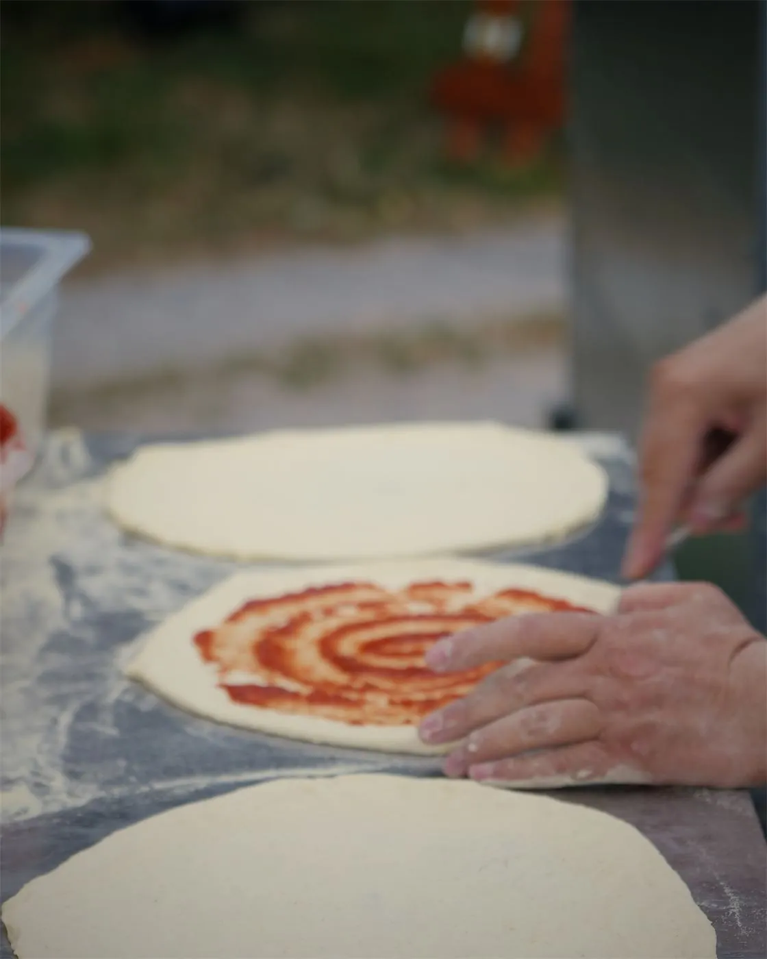 La sauce tomate étalée à la main sur la pâte à pizza